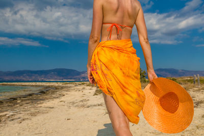 Low section of woman standing on beach against sky