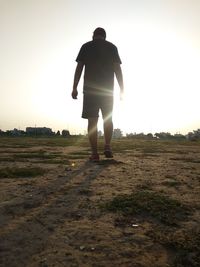 Rear view of man standing on field against sky