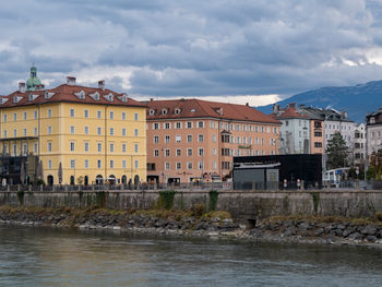 Buildings by river against sky