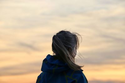 Rear view of woman against sky during sunset