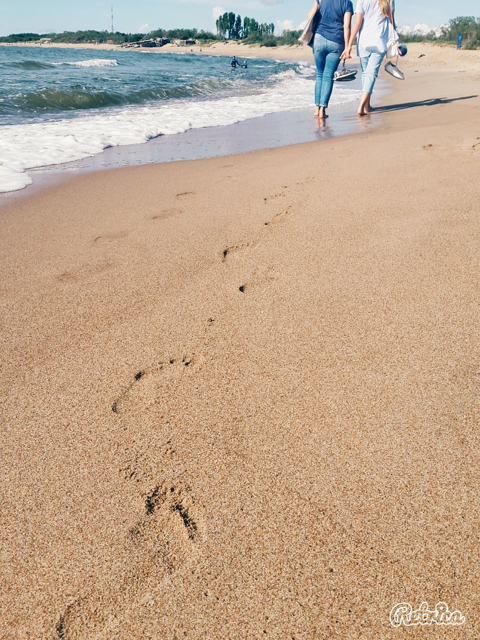 LOW SECTION OF MAN WALKING ON SANDY BEACH