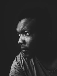 Close-up portrait of young man against black background