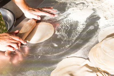 Cropped hand of person making chapatti on counter in kitchen at home