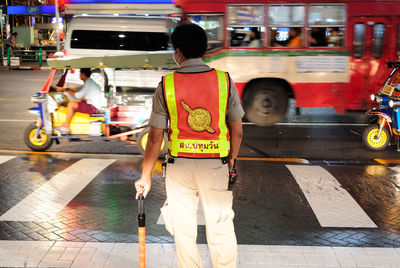 Rear view of traffic cop standing on city street at night