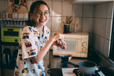 Portrait of young woman preparing food in kitchen