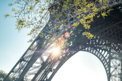 Low angle view of sunlight streaming through eiffel tower against sky