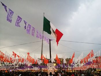 Crowd flags in city against sky