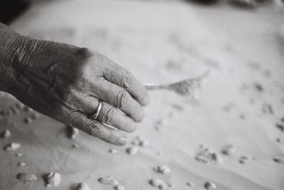 Cropped hand of senior woman having food at table