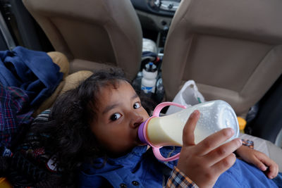 Portrait of girl drinking milk inside a car