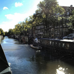 Canal amidst trees against sky