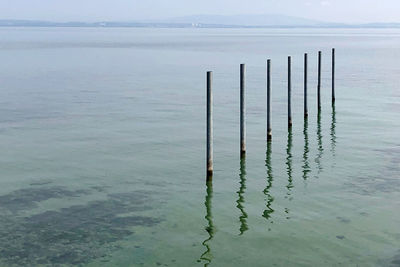 Wooden posts in sea against sky