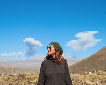 Young woman standing against sky