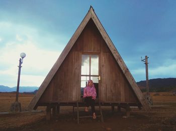 Woman by pink building against sky