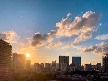 Modern buildings in city against sky during sunset