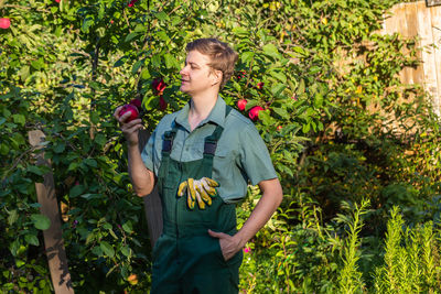 Portrait of young man standing against plants