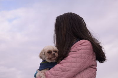 Portrait of woman with dog against sky