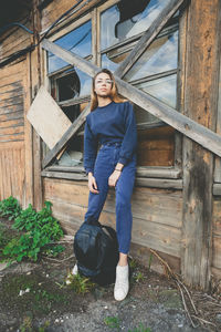 Portrait of smiling young woman standing against house