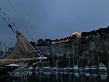Sailboats in building by mountains against sky at dusk