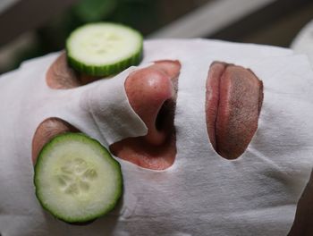 Close-up of man with cucumber and facial mask on face