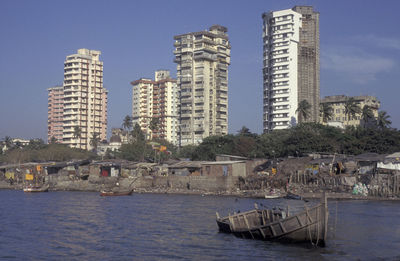 Buildings by river against sky