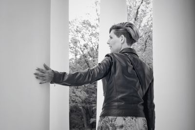 Side view of young woman looking away against wall