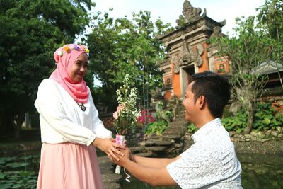 Smiling boyfriend giving bouquet to girlfriend in park