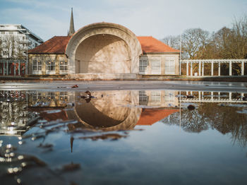 Arch bridge over lake by buildings against sky