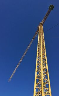 Low angle view of cranes against clear blue sky