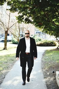 Businessman walking on footpath by tree