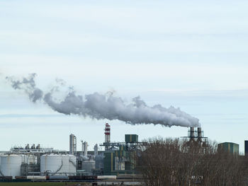 Smoke emitting from factory against sky