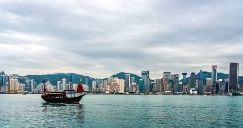 Sea by buildings against sky in city