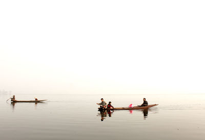 People on boat in sea against clear sky