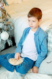 Boy in a white t-shirt and denim shirt. boy at home with popcorn. time at home. watching a movie 
