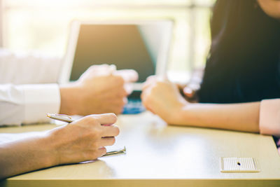 Midsection of woman holding hands on table