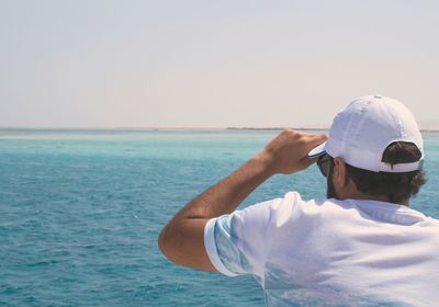 Man standing in sea against clear sky