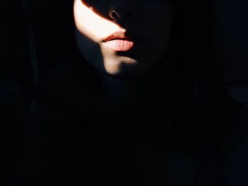 Sunlight falling on lips of woman in darkroom