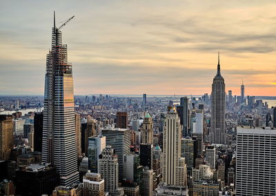 Aerial view of buildings in city against cloudy sky