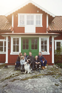 Smiling family sitting with pet at entrance of house