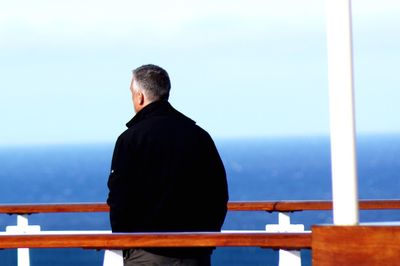 Rear view of man looking at sea against sky