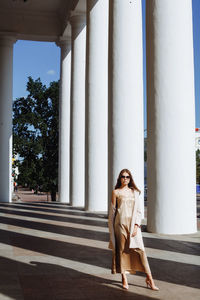 Full length of fashionable young woman standing by building in city