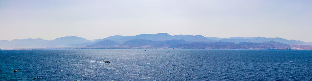 Scenic view of sea by mountains against sky