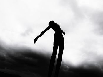 Low angle view of silhouette woman standing against sky