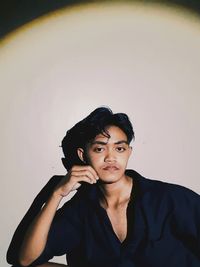 Portrait of young man standing against wall