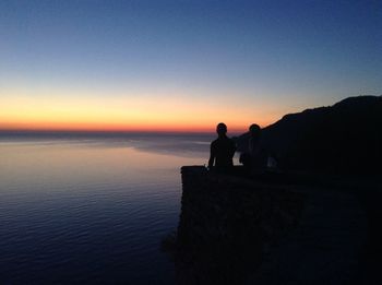 Silhouette of people in sea at sunset