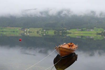 Boat moored on lake against trees