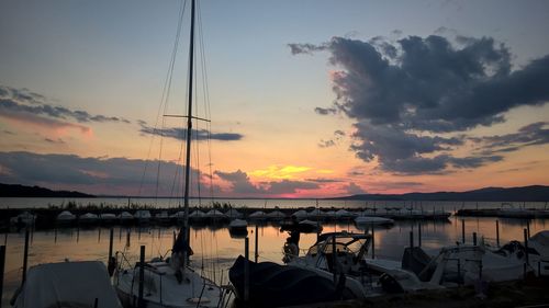 Sailboats moored in sea during sunset