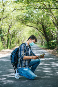 Young man using mobile phone while sitting on road