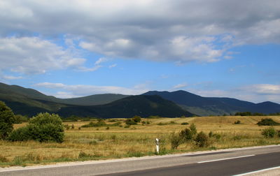 Scenic view of road by mountains against sky