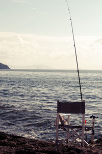 Chair on beach against sky