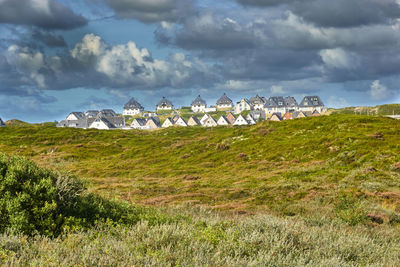 Small vacation homes on the horizon on the dunes overgrown with beach grass under a cloudy sky